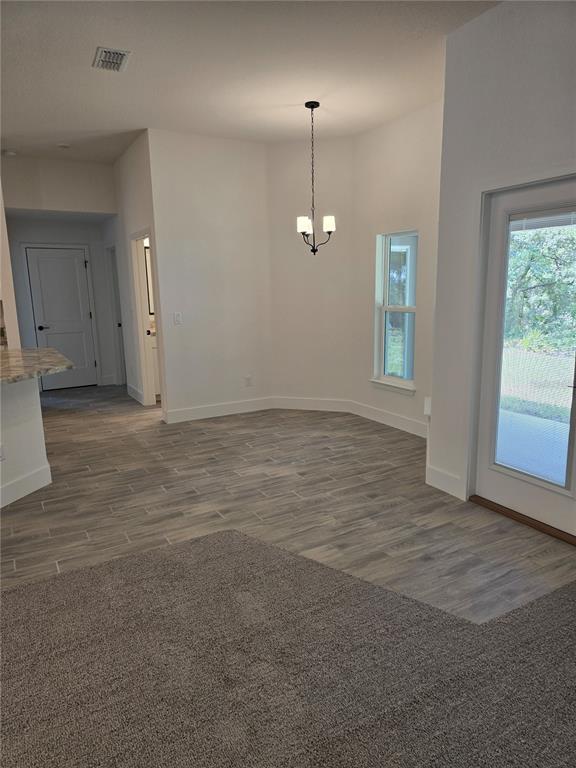 An open dining area features wood-look tile flooring, a chandelier, and a glass patio door — 13 GERANIUM COURT, HOMOSASSA, FL