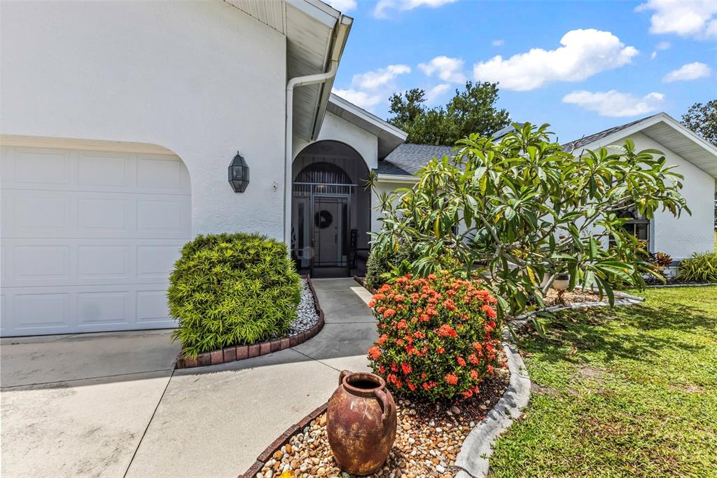 A white house exterior features a garage, a walkway, and a landscaped front garden — 239 VALDIVA STREET, PUNTA GORDA, FL