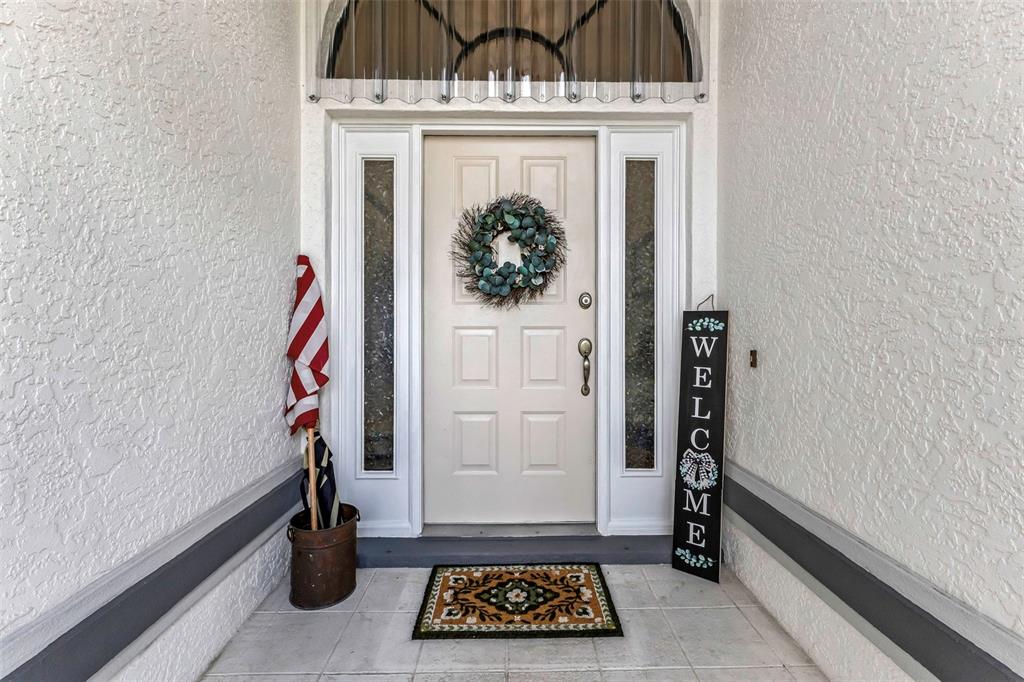 A front entryway features a white door with a wreath, a welcome sign, and flag — 239 VALDIVA STREET, PUNTA GORDA, FL