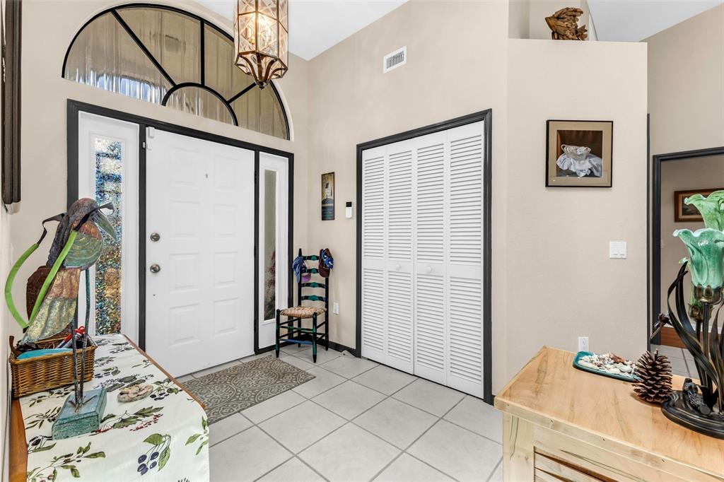 A tiled entryway features a white front door, a louvered closet, and decorative accent pieces — 239 VALDIVA STREET, PUNTA GORDA, FL
