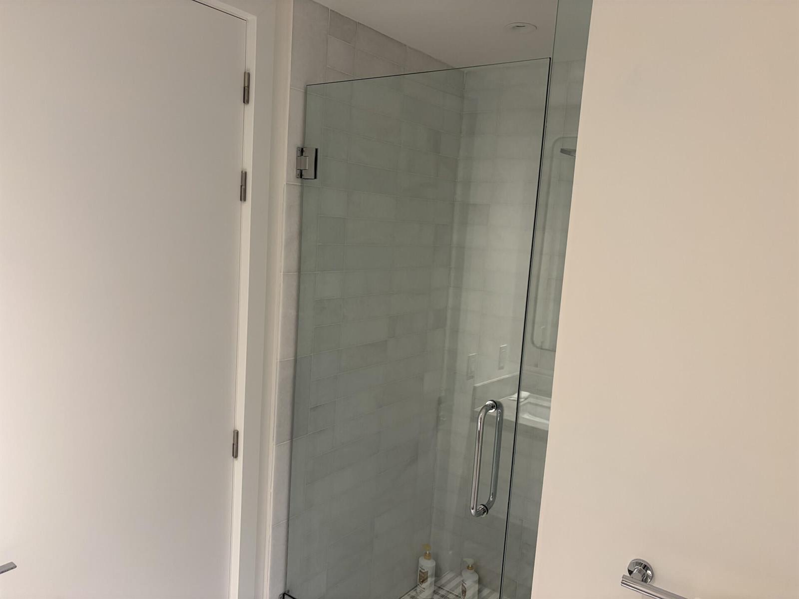 A glass shower door with a chrome handle is installed in a tiled bathroom — 700 NE 26th Terrace # 2006, Miami FL 33137, MIAMI, FL