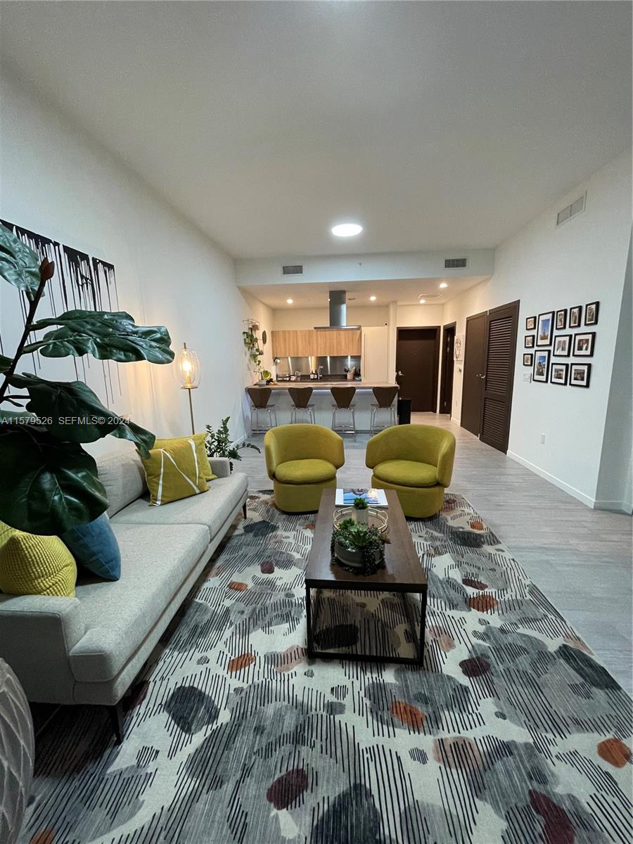 A living room with a sofa, two yellow chairs, and a kitchen in the background — 1000 Brickell Plz # 1811, Miami FL 33131, MIAMI, FL