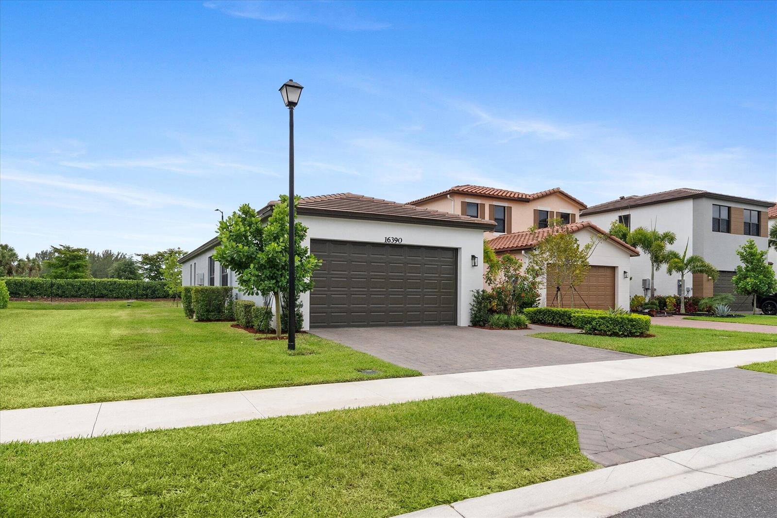 A single-story house with a dark garage door, a paved driveway, and a front lawn — 16390 Sea Turtle Place, FL 33470, FL