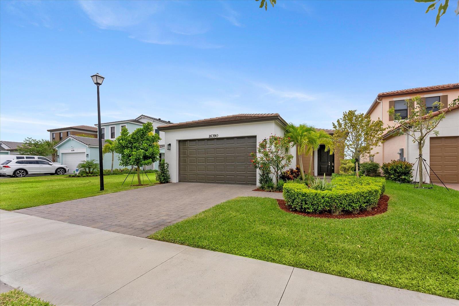 A single-story house with a brown garage door, a paved driveway, and a manicured front lawn — 16390 Sea Turtle Place, FL 33470, FL