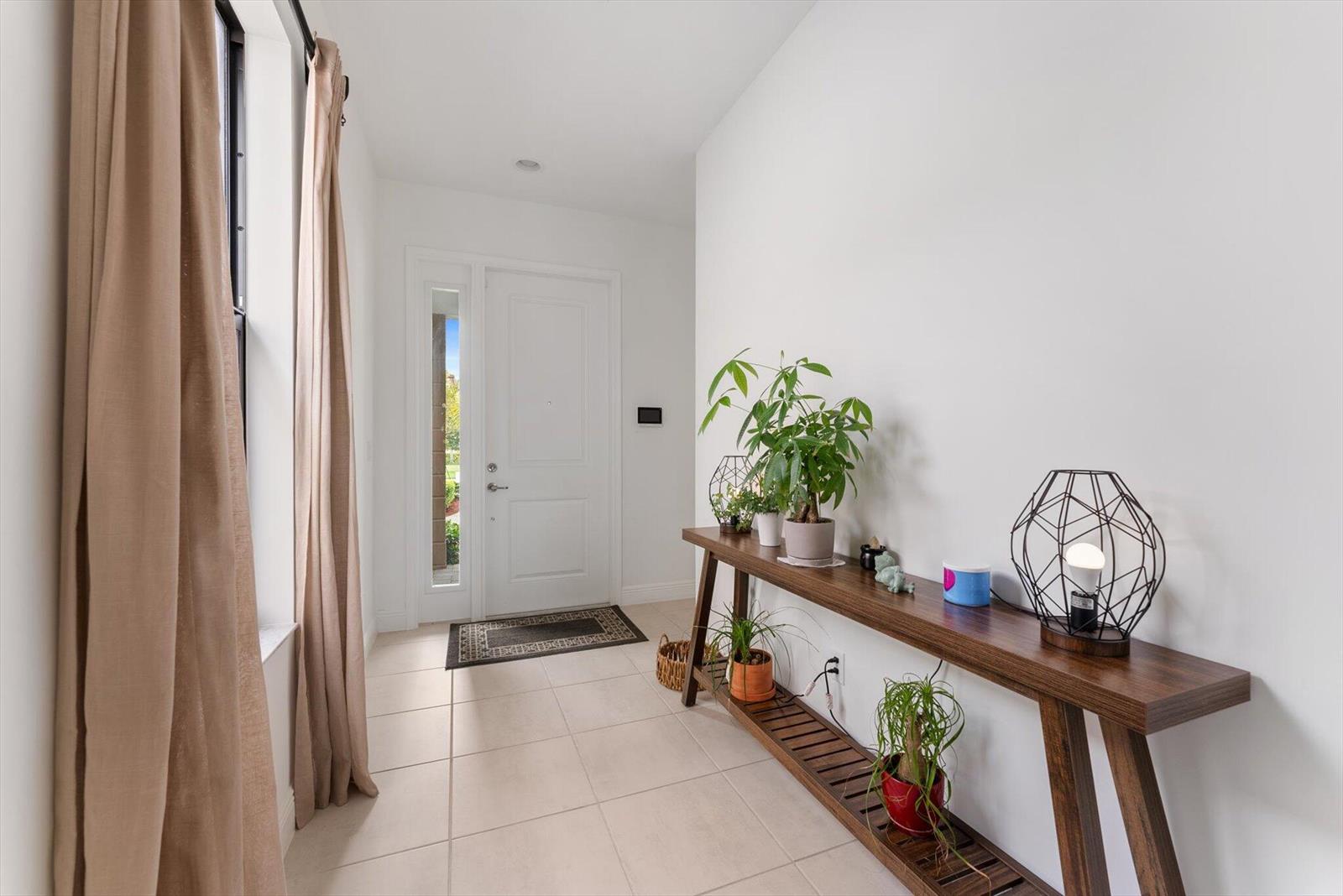 A bright entryway features a white door, tiled floors, and a long wooden console table — 16390 Sea Turtle Place, FL 33470, FL