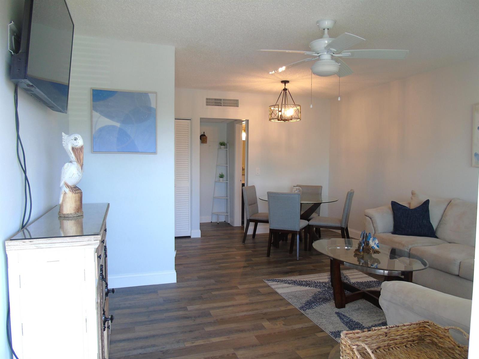 A living and dining area with wood-look flooring, a ceiling fan, and neutral furniture — 309 Circle Drive S # 204, Boynton Beach FL 33435, BOYNTON BEACH, FL