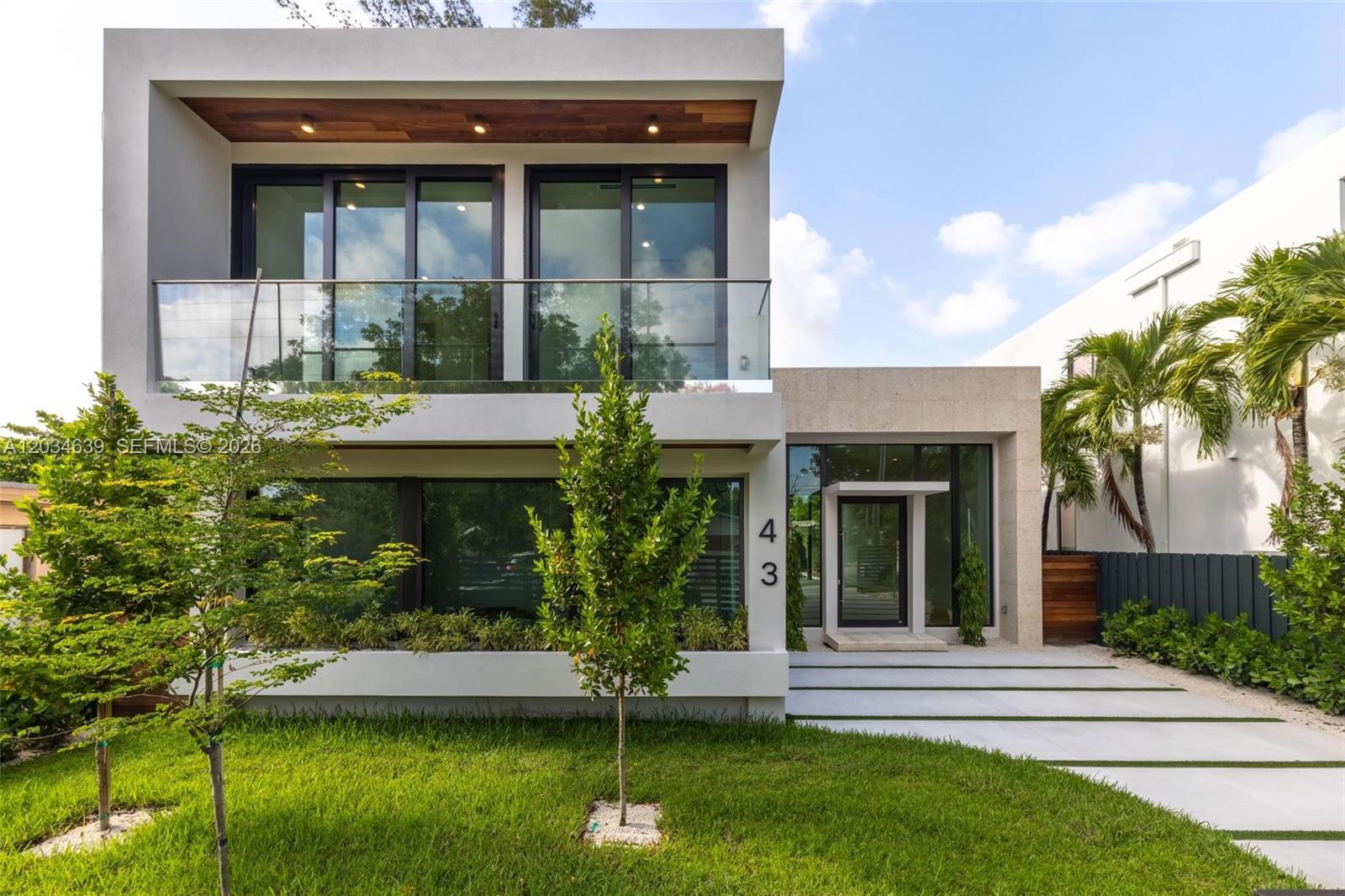 A modern two-story house features a glass balcony, large windows, and a stone-paved entryway — 43 NW 42nd St, Miami FL 33127, MIAMI, FL