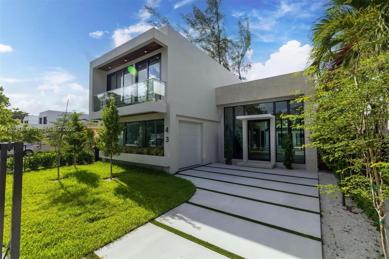 A modern two-story house features a white exterior, glass balcony, and a paved driveway — 43 NW 42nd St, Miami FL 33127, MIAMI, FL