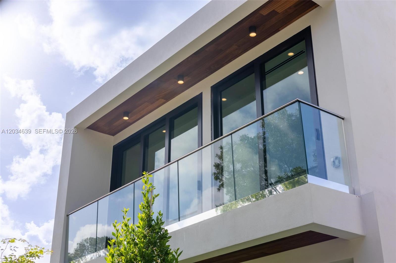 A modern building exterior features a glass-railed balcony with wood-paneled soffit and recessed lighting — 43 NW 42nd St, Miami FL 33127, MIAMI, FL