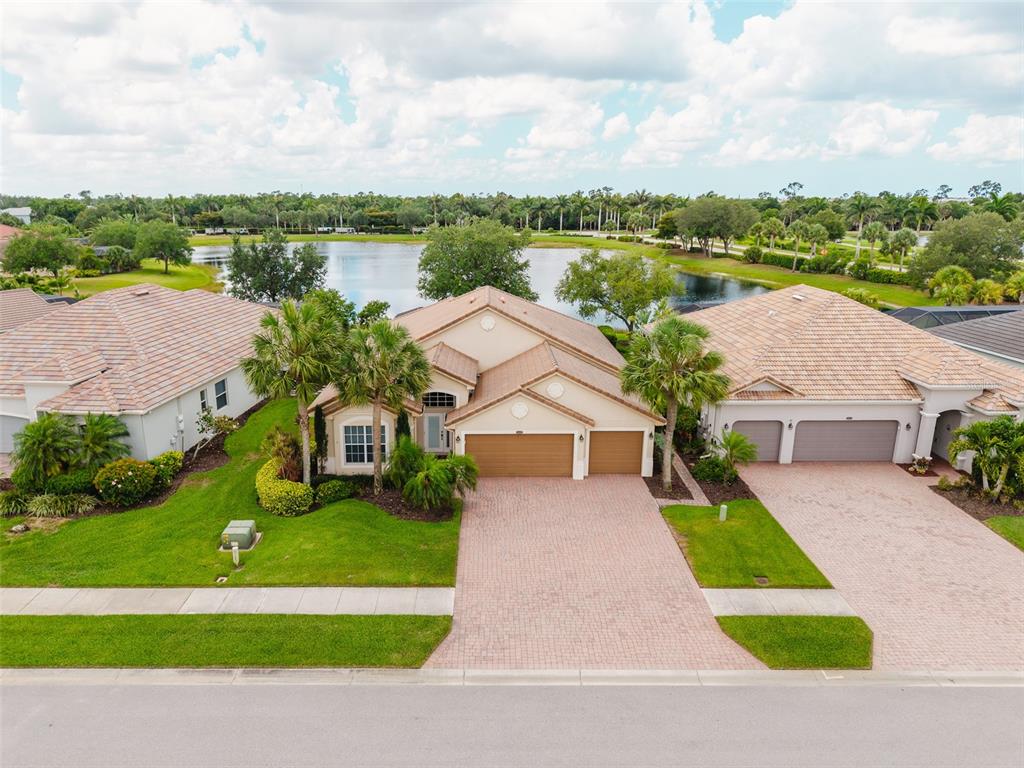 An aerial view shows a suburban house with a tiled roof and paver driveway — 25019 PURPLE EMPEROR WAY, PUNTA GORDA, FL