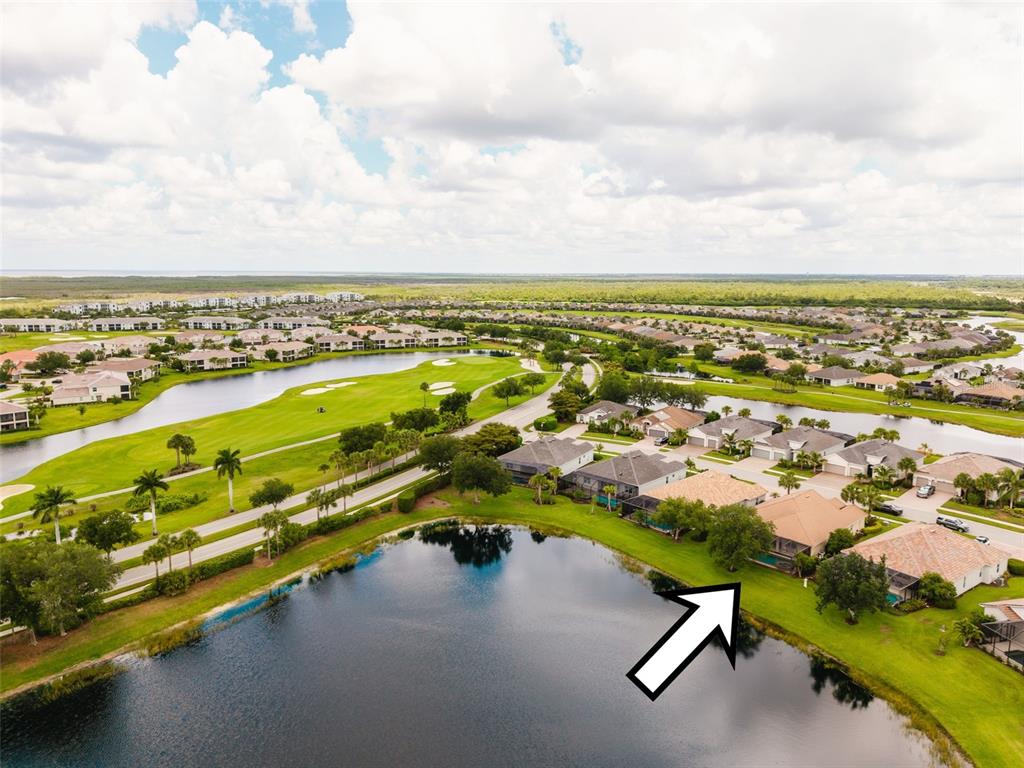 An aerial view shows a residential neighborhood with houses situated along a lake and golf course — 25019 PURPLE EMPEROR WAY, PUNTA GORDA, FL
