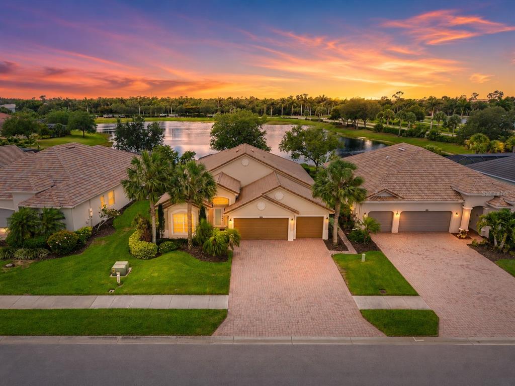 An aerial view of a suburban house with a brick driveway at sunset — 25019 PURPLE EMPEROR WAY, PUNTA GORDA, FL