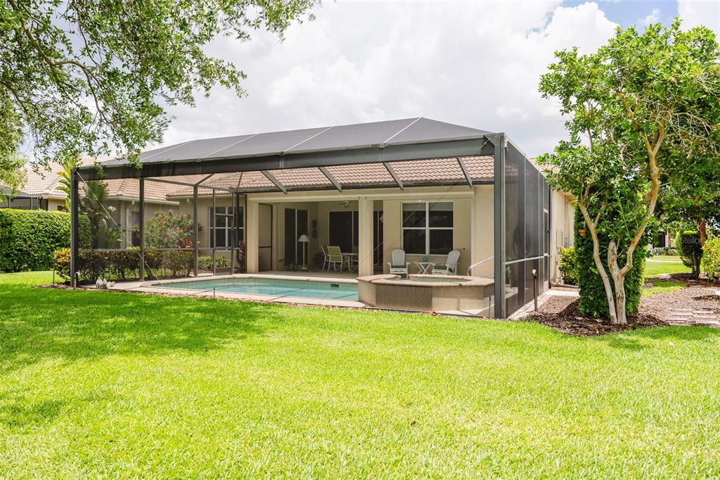 A backyard view of a house with a screened-in pool, spa, and covered patio — 25019 PURPLE EMPEROR WAY, PUNTA GORDA, FL