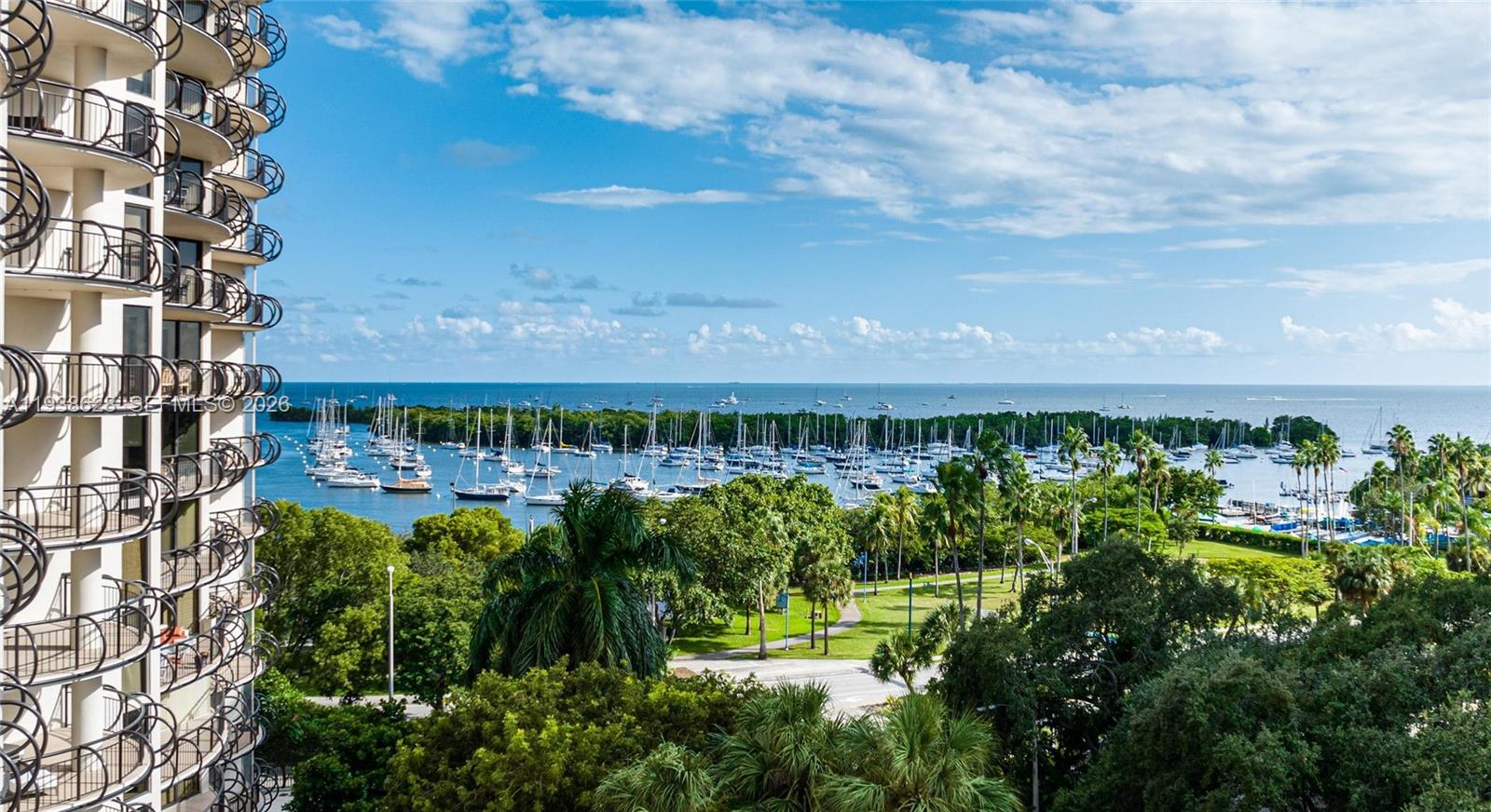 A high-angle view shows a balcony overlooking a marina filled with boats and trees — 2843 S Bayshore Dr # 6B, Miami FL 33133, MIAMI, FL