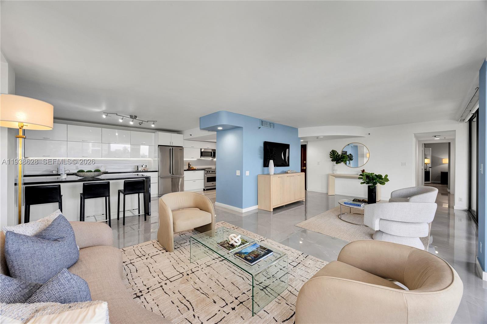 A modern open-concept living room and kitchen feature light blue accent walls and tile flooring — 2843 S Bayshore Dr # 6B, Miami FL 33133, MIAMI, FL