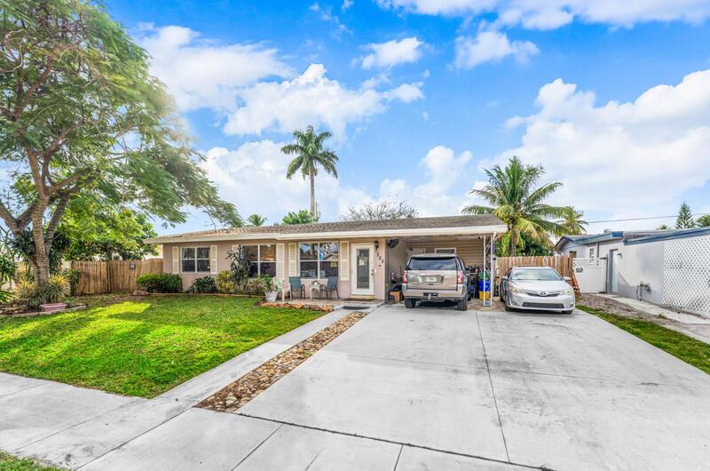 A single-story house with a concrete driveway, a carport, and a front lawn — 305 Henthorne Drive, Palm Springs FL 33461, PALM SPRINGS, FL
