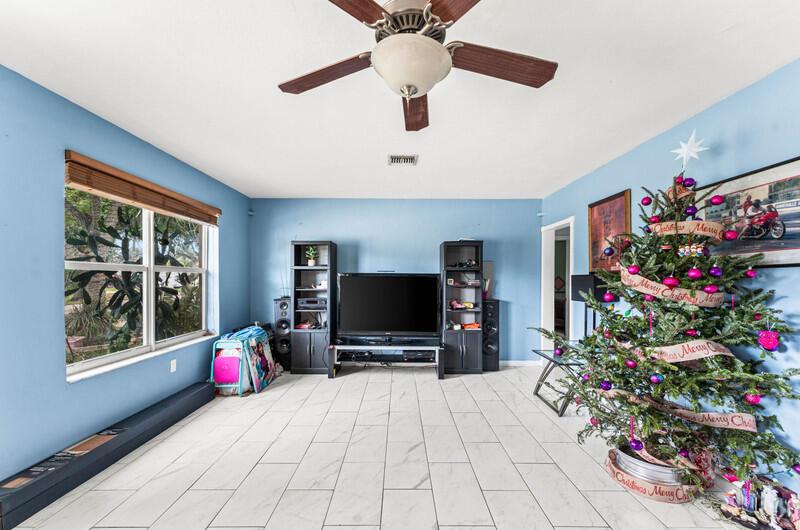 A living room with blue walls, white tile flooring, a ceiling fan, and a Christmas tree — 305 Henthorne Drive, Palm Springs FL 33461, PALM SPRINGS, FL