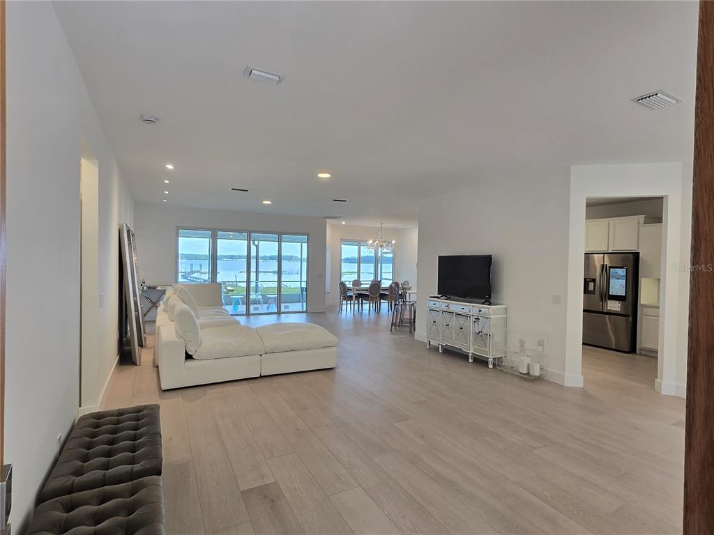 An open-concept living and dining area features light wood flooring and a view of water — 560 EDEN DRIVE, ST CLOUD, FL
