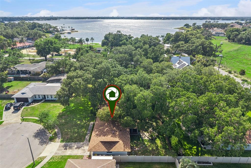 An aerial view shows a house with a brown roof surrounded by trees near water — 4101 PLAYA COURT, BELLE ISLE, FL
