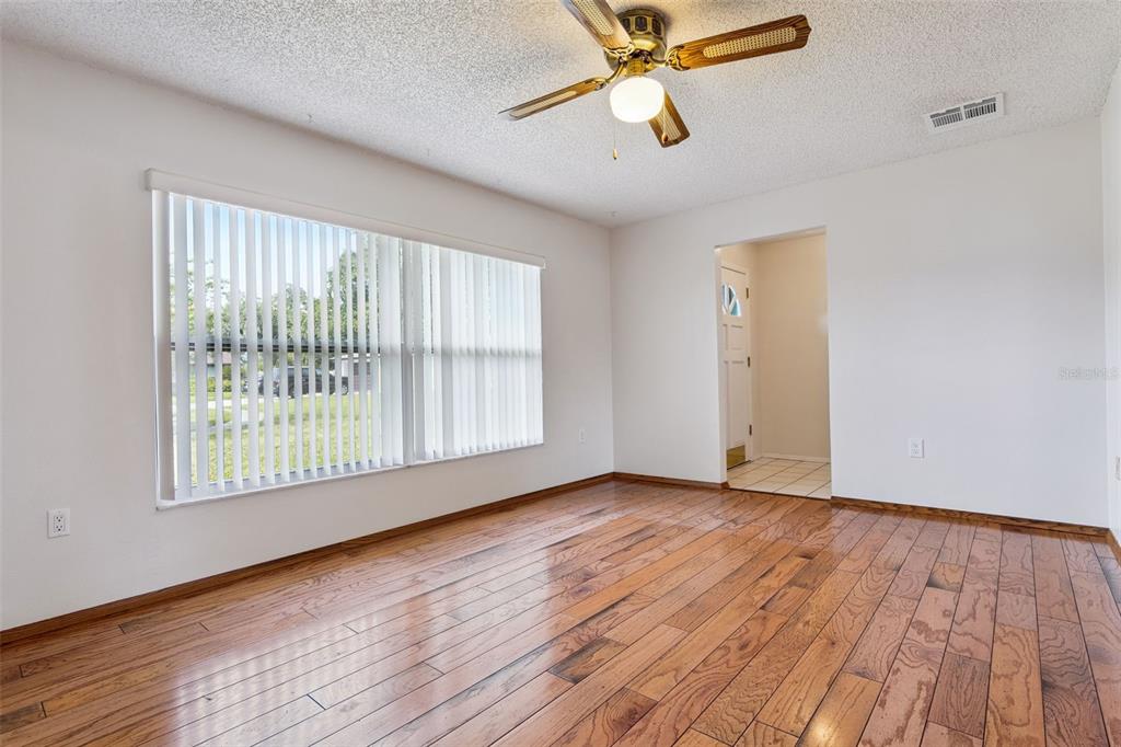 An empty living room features hardwood floors, a ceiling fan, and white walls — 4101 PLAYA COURT, BELLE ISLE, FL