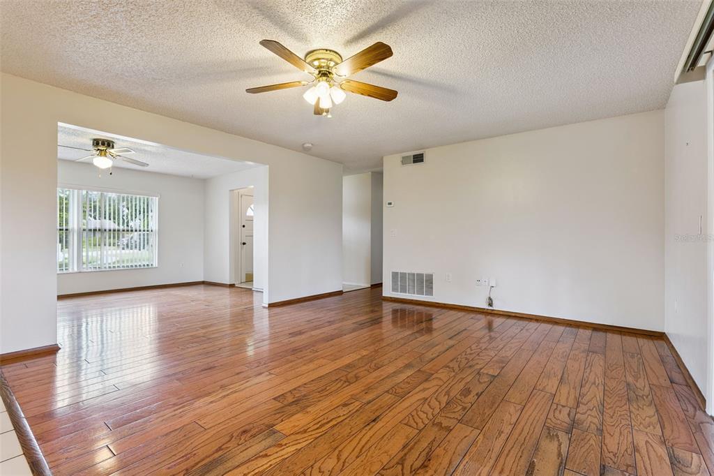 A living room with hardwood floors opens to a kitchen with wood cabinets and tile flooring — 4101 PLAYA COURT, BELLE ISLE, FL