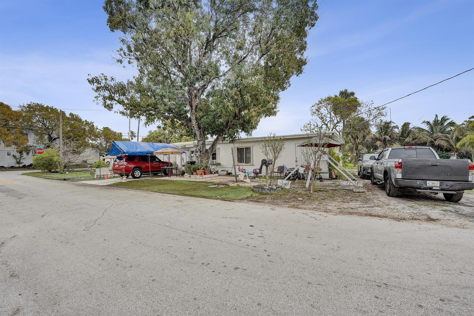A single-story house with a large tree, a red SUV under a tarp, and a truck — 630 NW 15th Avenue, Pompano Beach FL 33069, POMPANO BEACH, FL