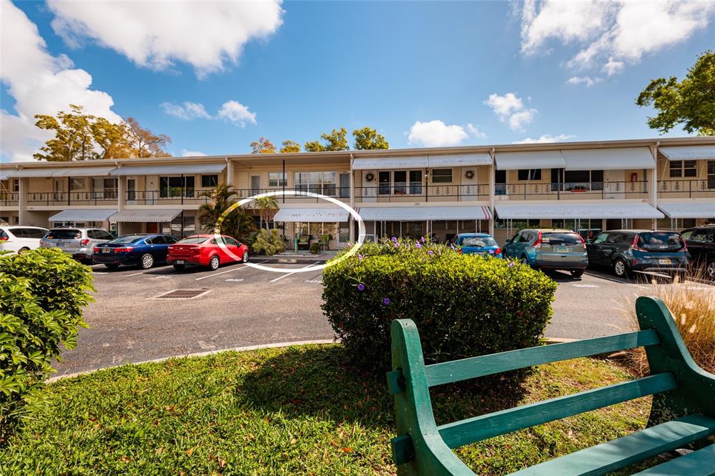 A multi-story apartment building exterior features a parking lot and a green bench — 4143 56TH STREET N UNIT 903, KENNETH CITY, FL