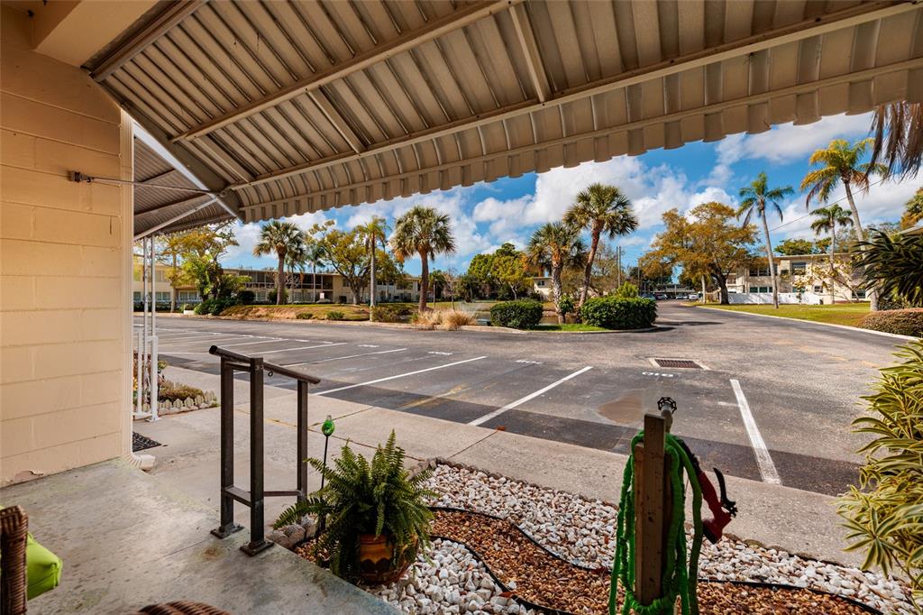 A view from a covered patio looking out toward a parking lot and palm trees — 4143 56TH STREET N UNIT 903, KENNETH CITY, FL