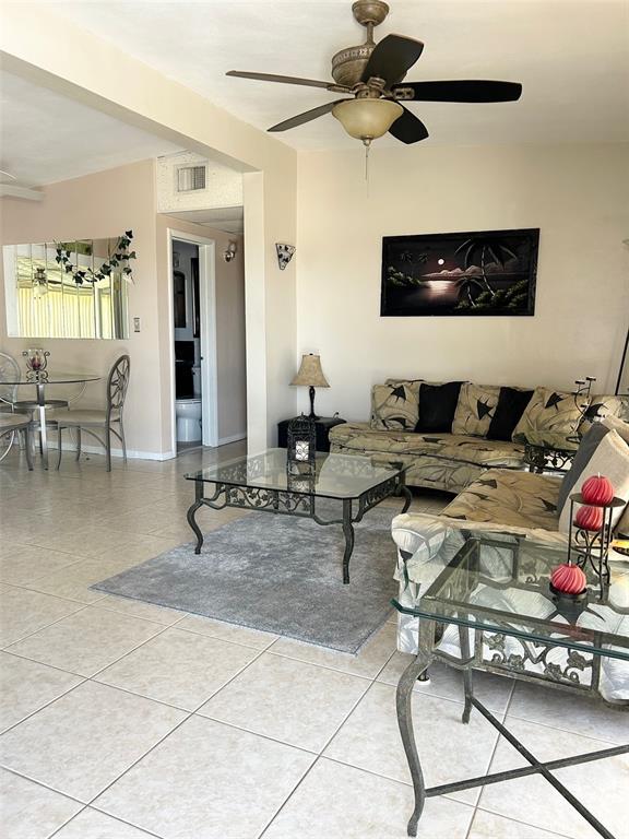 A living room features tile floors, a ceiling fan, a glass coffee table, and seating — 123 POINSETTIA CIRCLE NE, PORT CHARLOTTE, FL