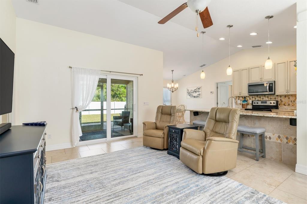 A living room with two tan recliners, a rug, and an open kitchen with bar seating — 4352 ADELAIDE AVENUE, NORTH PORT, FL