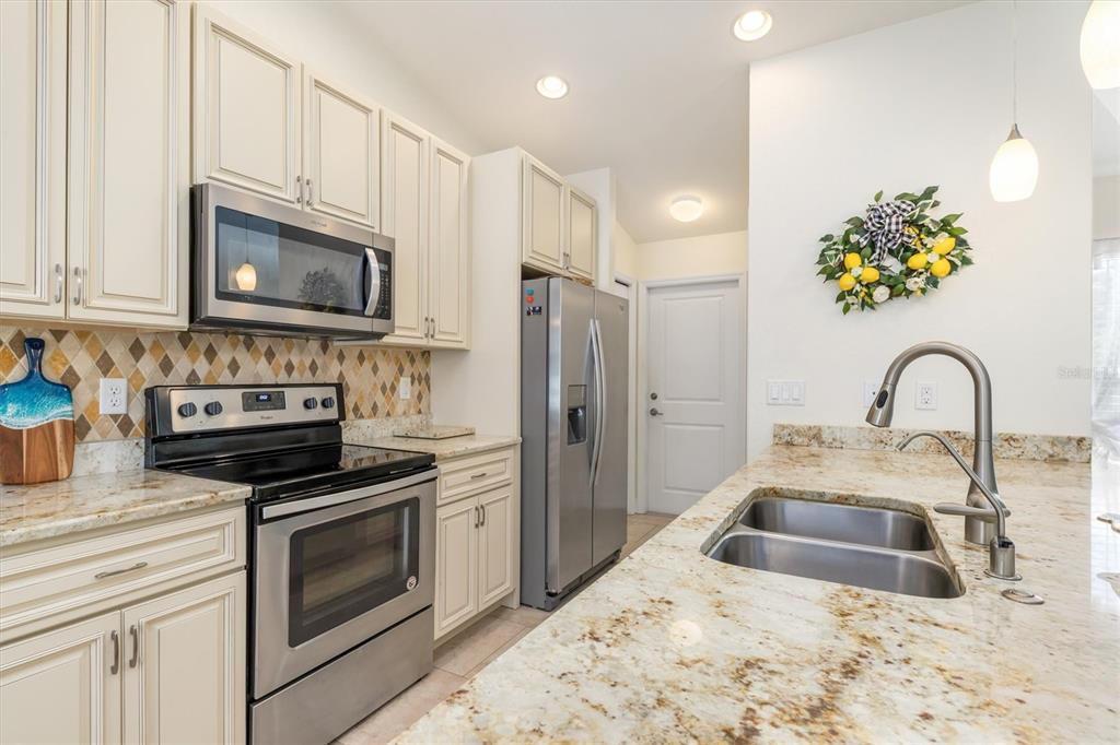 A kitchen features cream cabinets, granite countertops, stainless steel appliances, and a double-basin sink — 4352 ADELAIDE AVENUE, NORTH PORT, FL