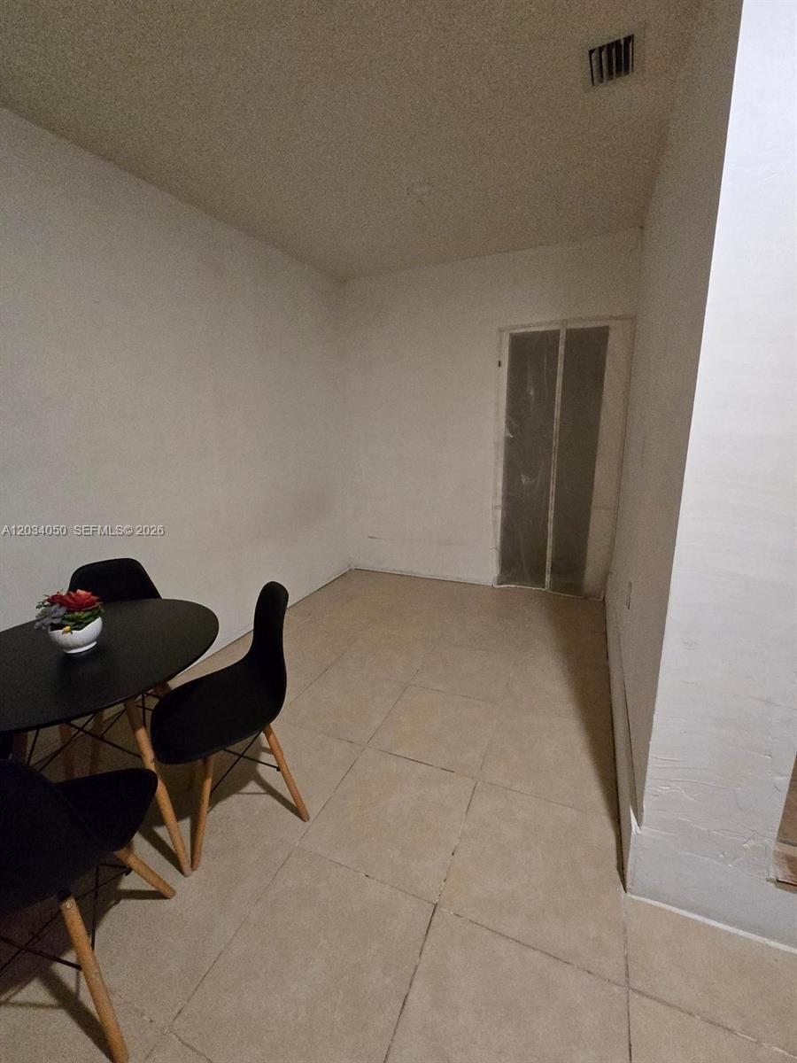 A dining area features a small round table, black chairs, and light-colored tile flooring — 4863 SW 148th Ct # 1, Miami FL 33185, MIAMI, FL