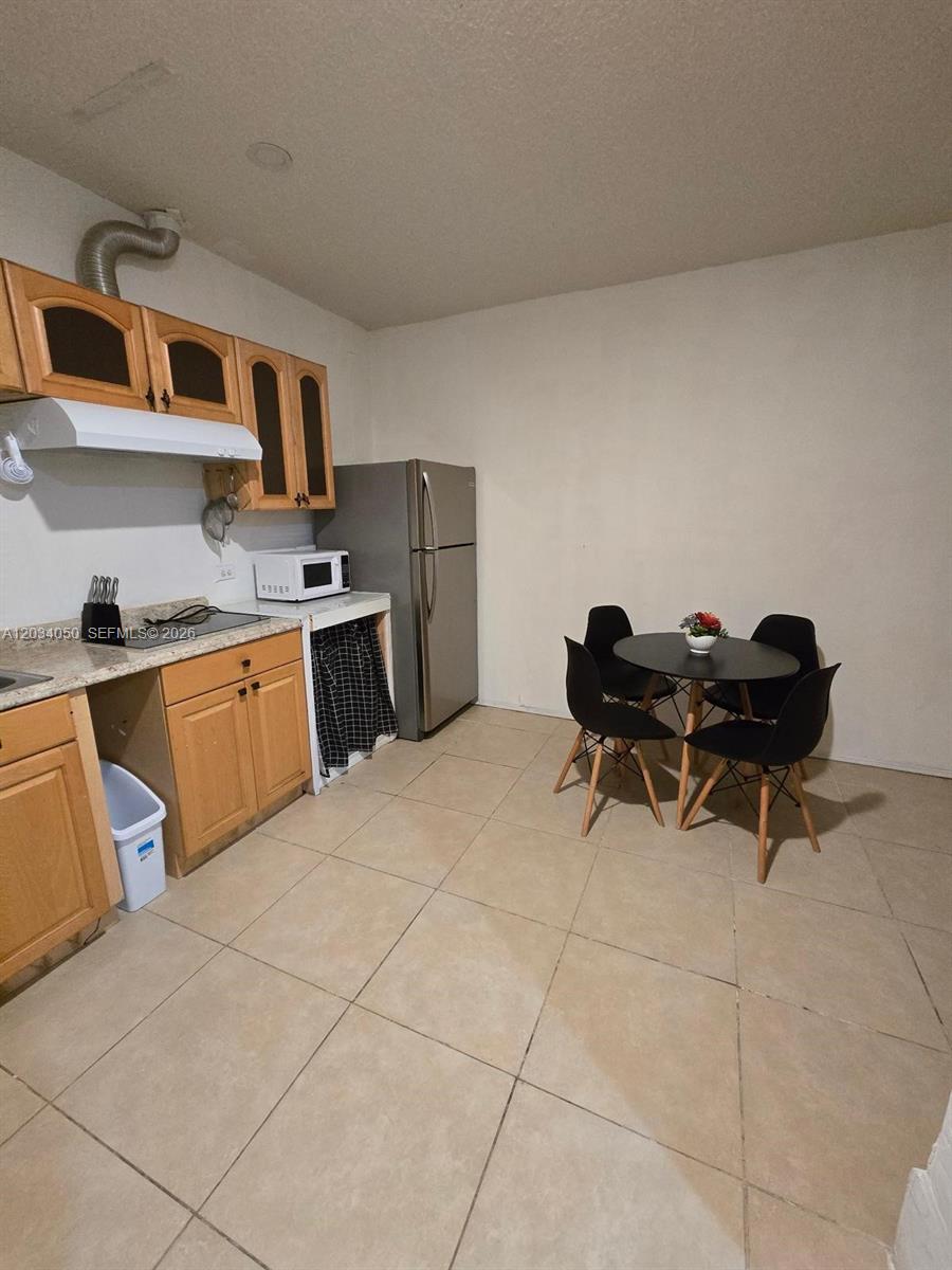 A kitchen features light wood cabinets, granite countertops, a stainless refrigerator, and a dining set — 4863 SW 148th Ct # 1, Miami FL 33185, MIAMI, FL