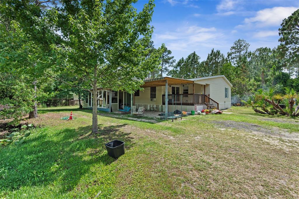 A single-story house with a covered wooden deck and patio sits on a grassy lot — 2094 ELDER STREET, BUNNELL, FL