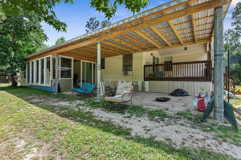 A covered patio area with a wooden deck and a screened-in porch at the house — 2094 ELDER STREET, BUNNELL, FL