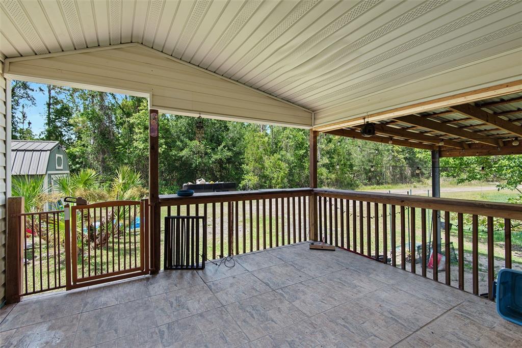 A covered outdoor patio features tiled flooring, a wooden railing, and a gated entrance — 2094 ELDER STREET, BUNNELL, FL