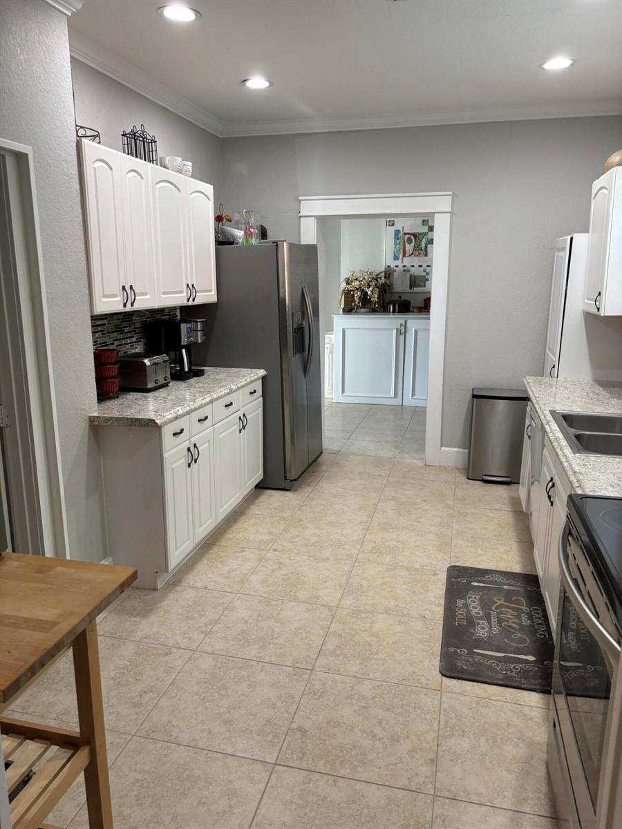 A kitchen features white cabinets, granite countertops, stainless steel appliances, and light tile flooring — 808 Kanuga Drive, West Palm Beach FL 33401, WEST PALM BEACH, FL