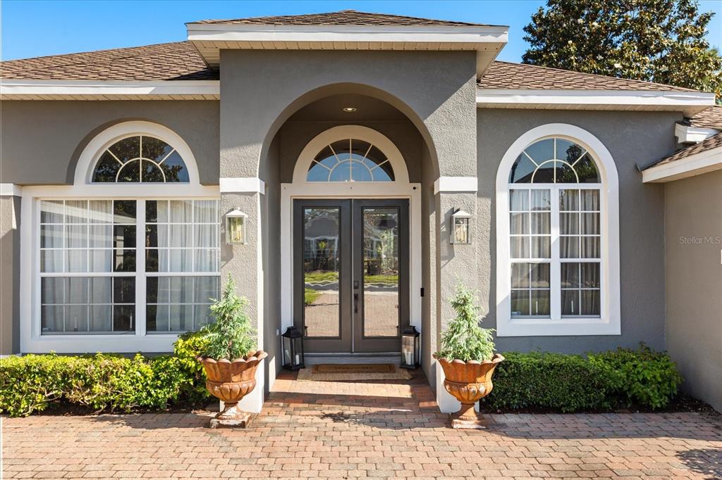 The exterior of a house features a brick walkway, double front doors, and arched windows — 2210 NORTHUMBRIA DRIVE, SANFORD, FL