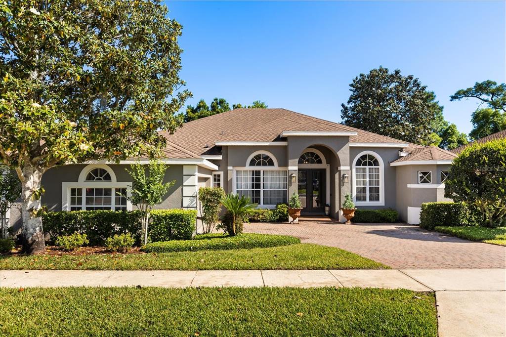 A single-story house with a gray exterior, arched windows, and a brick paver driveway — 2210 NORTHUMBRIA DRIVE, SANFORD, FL