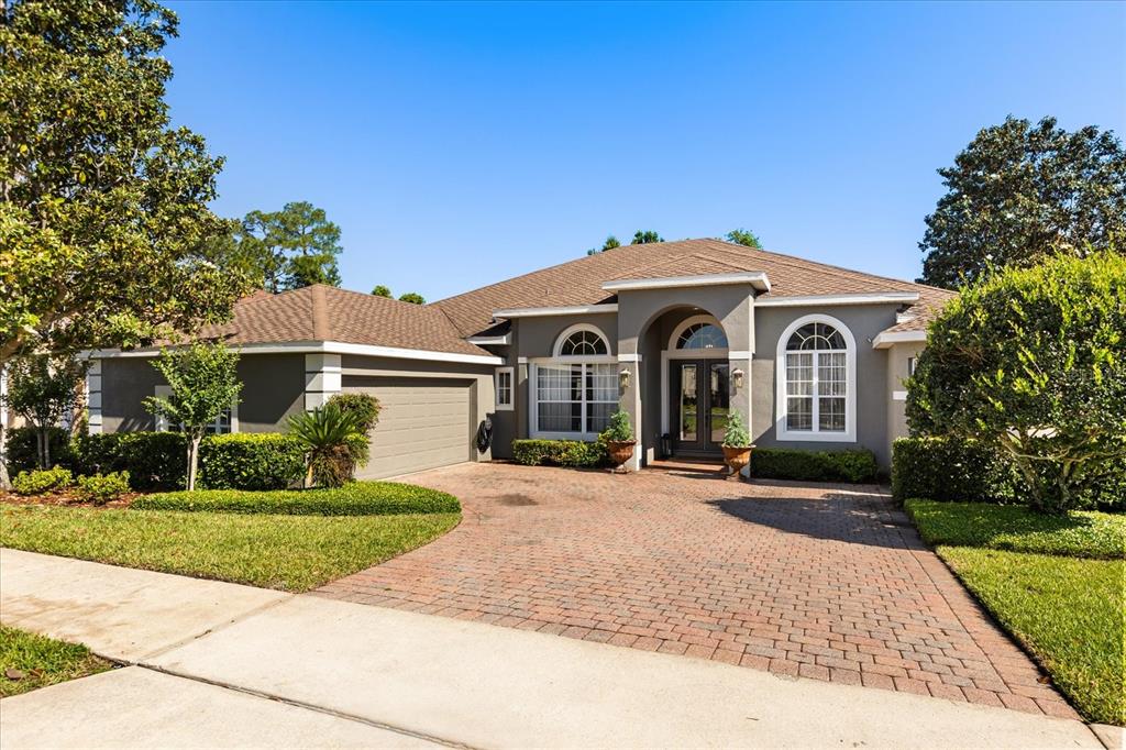 A single-story house with a brick paver driveway, a two-car garage, and arched windows — 2210 NORTHUMBRIA DRIVE, SANFORD, FL