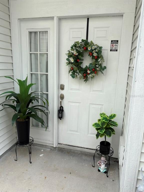 A white front door with a wreath, sidelight, and two potted plants on metal stands — 1948 CRANBERRY ISLES WAY, APOPKA, FL