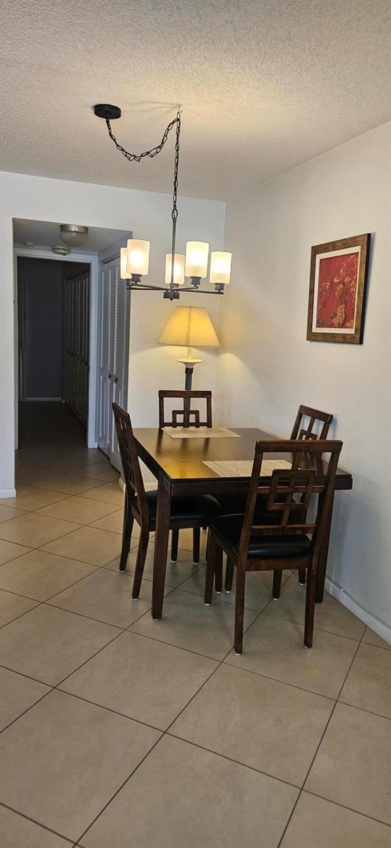 A dining area features a dark wood table, four chairs, and a hanging light fixture — 27 Newport B, Deerfield Beach FL 33442, DEERFIELD BEACH, FL
