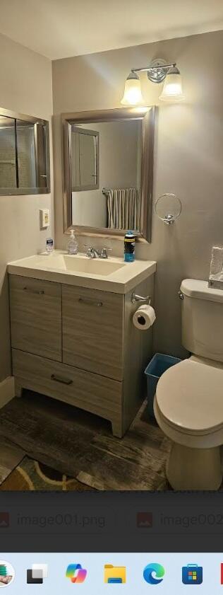 A bathroom features a wood-grain vanity, a rectangular mirror, and a white toilet — 27 Newport B, Deerfield Beach FL 33442, DEERFIELD BEACH, FL