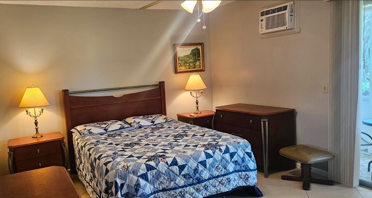 A bedroom features a bed with a blue and white quilt, two nightstands, and furniture — 27 Newport B, Deerfield Beach FL 33442, DEERFIELD BEACH, FL