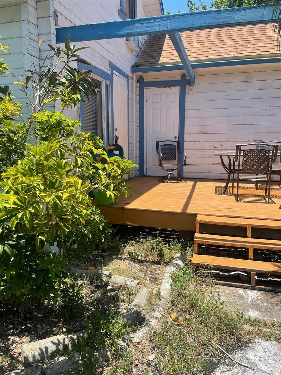 A wooden deck with outdoor furniture sits in front of a white house with blue trim — 611 N Broadway # A, Lantana FL 33462, LANTANA, FL