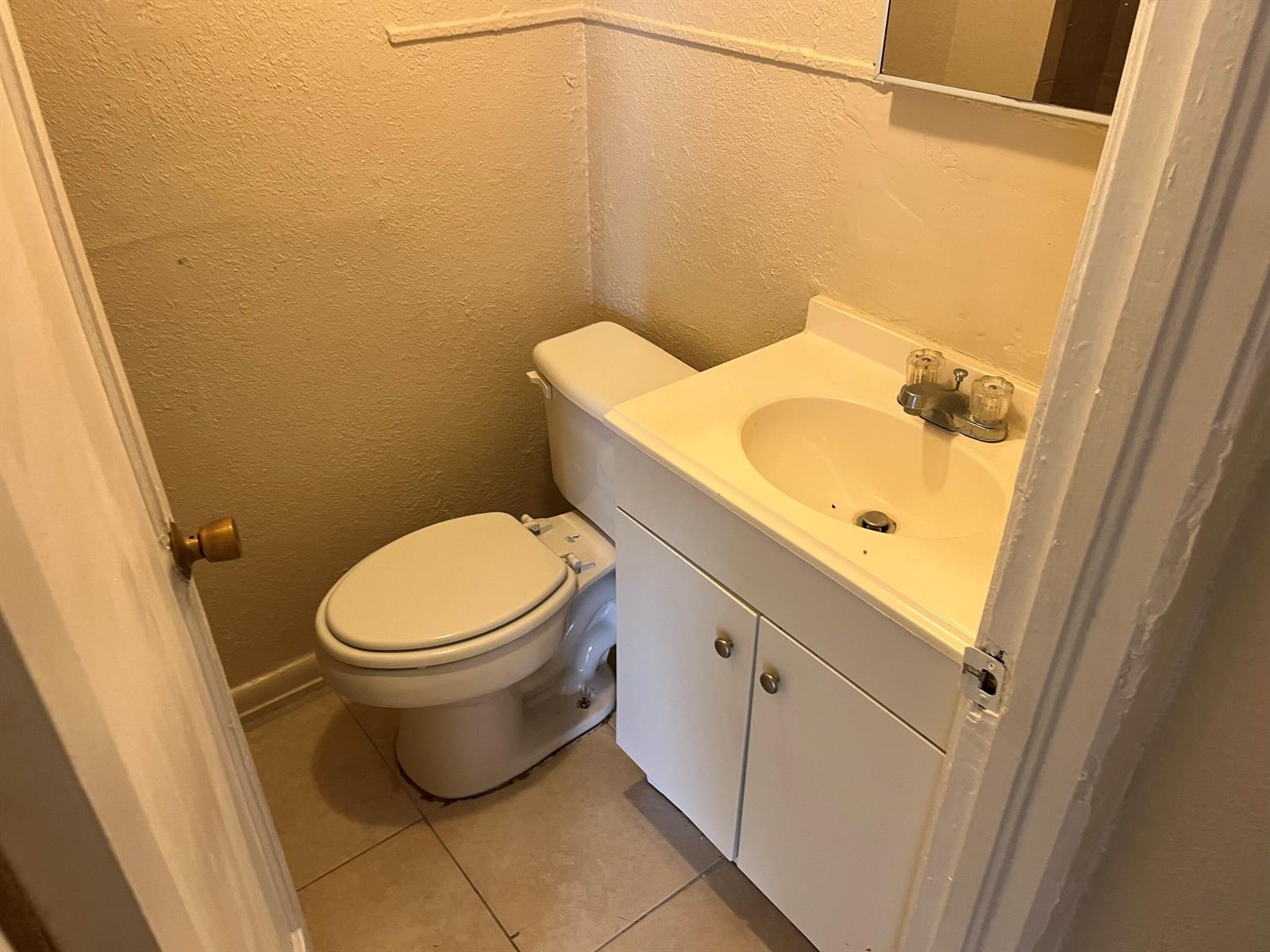 A small bathroom featuring a white toilet, a vanity with a sink, and tiled flooring — 611 N Broadway # A, Lantana FL 33462, LANTANA, FL