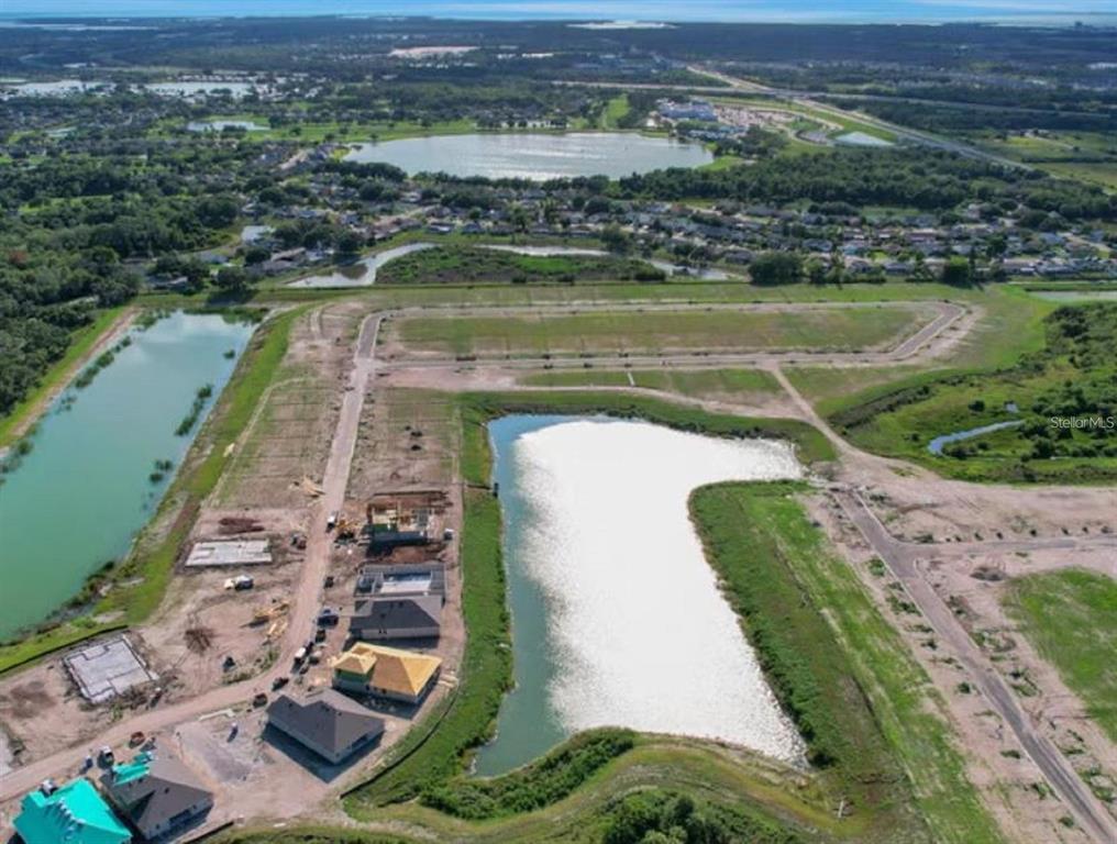An aerial view shows a residential construction site with several houses and a large pond — 8116 SUNNY POINT TRAIL, PARRISH, FL