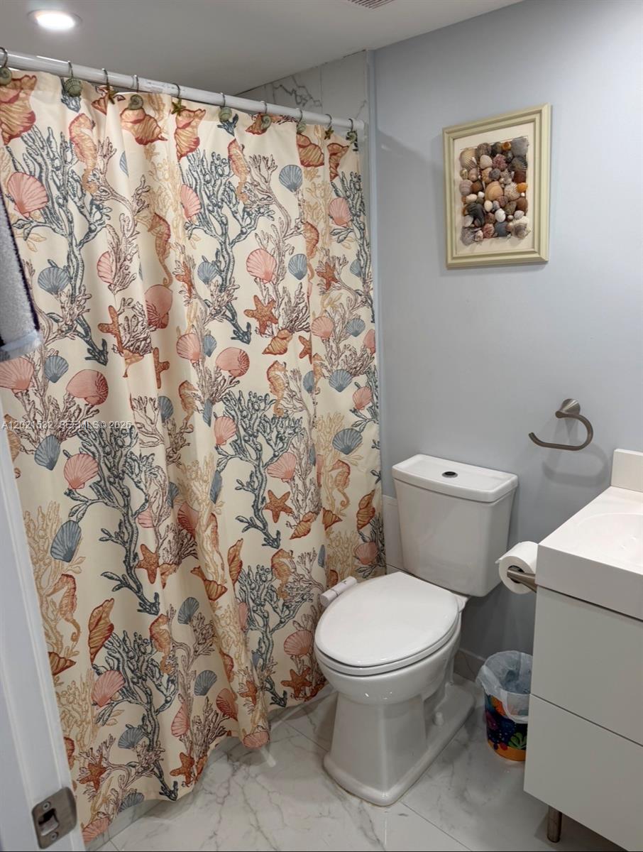 A bathroom features a seashell-patterned shower curtain, a white toilet, and a wall-mounted shell display — 3140 S Ocean Dr # 1003, Hallandale Beach FL 33009, HALLANDALE BEACH, FL