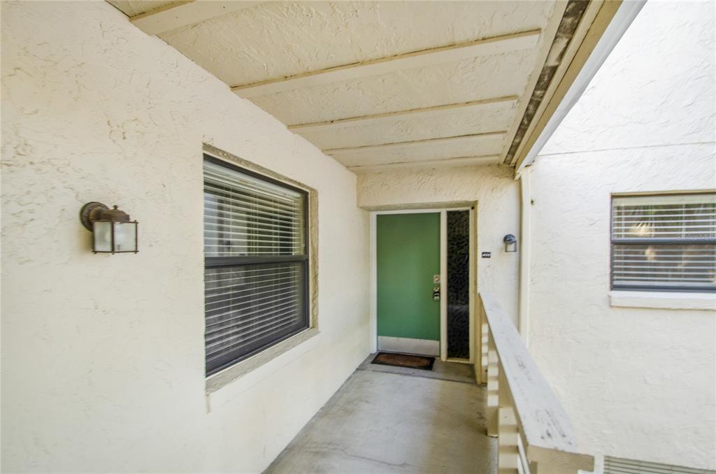 A covered exterior walkway leads to a green front door with a side window panel — 439 S NETHERWOOD CRESCENT UNIT 439, ALTAMONTE SPRINGS, FL