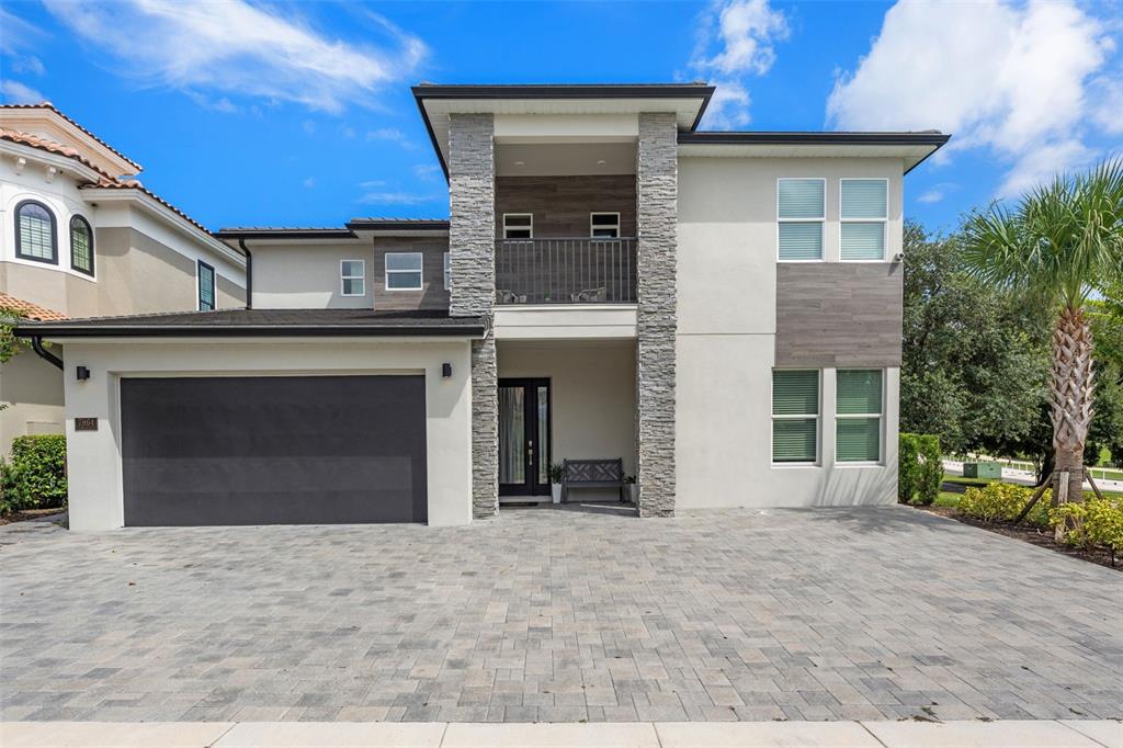 A two-story house with a stone-accented facade, a balcony, and a paved driveway — 7864 PALMILLA COURT, REUNION, FL
